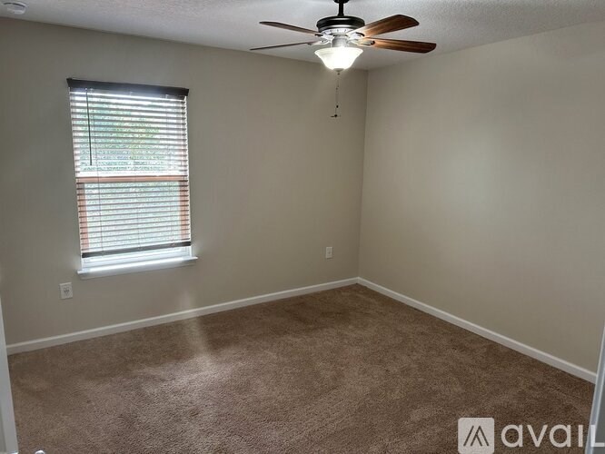 A room with a ceiling fan and a window with blinds.