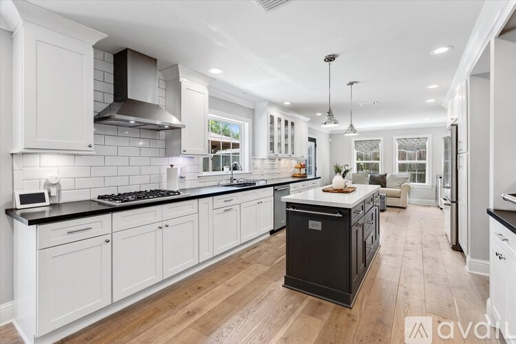 A modern kitchen with white cabinets and a black stove top.