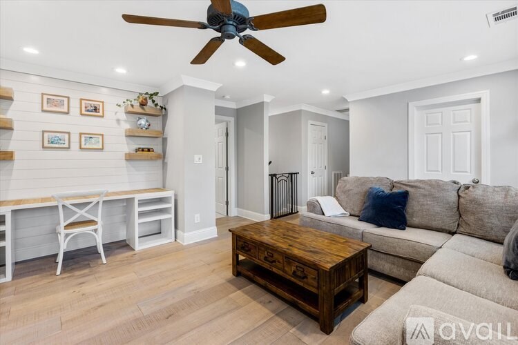 A living room with a couch, coffee table, and a fan.
