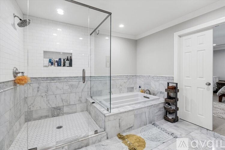 A bathroom with a marble floor and a glass shower stall.