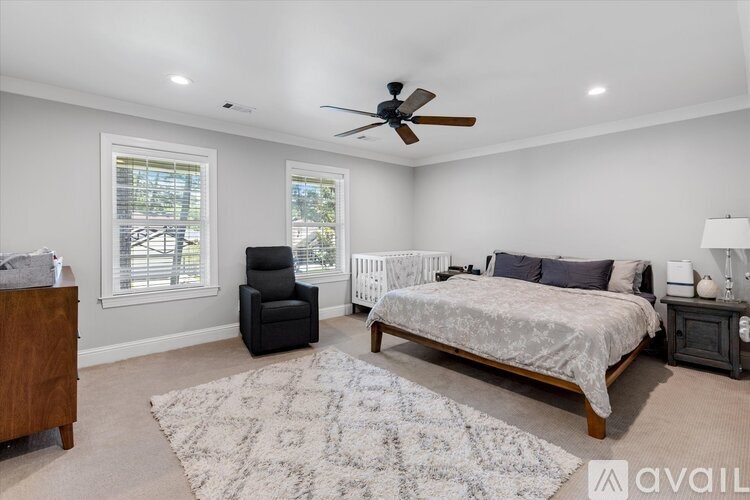 A bedroom with a large bed, a chair, and a fan.