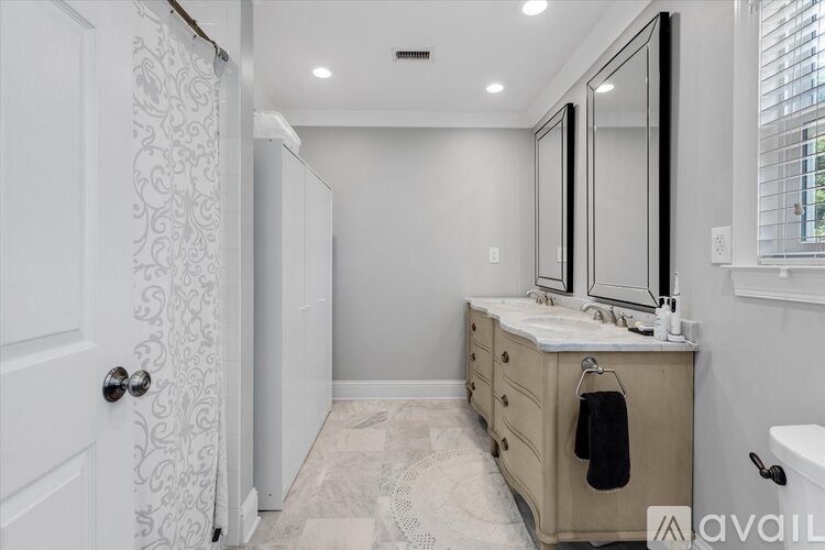 A bathroom with a vanity, mirror, and a towel hanging on the door.