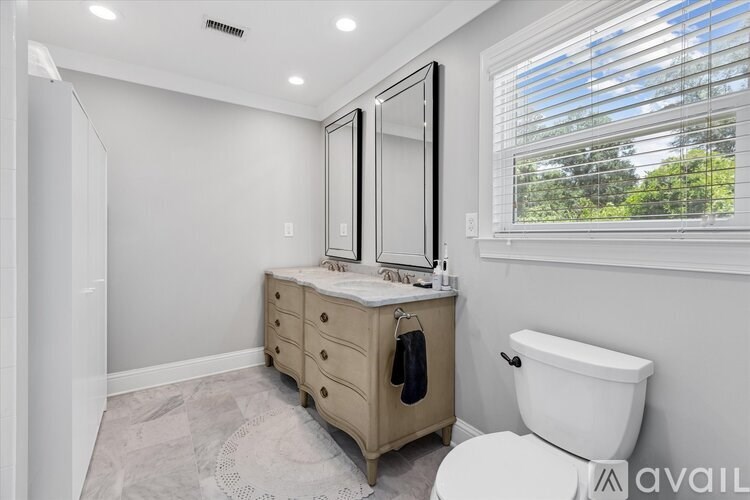 A bathroom with a toilet, sink, and a window with blinds.