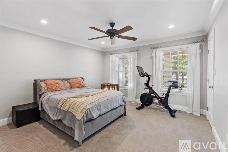 A bedroom with a bed, a fan, and a window with a view of trees.