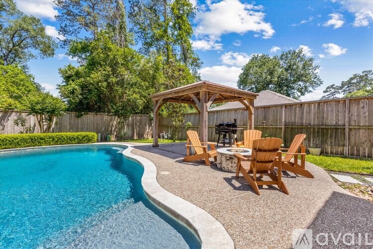 A pool with a wooden table and chairs is surrounded by a wooden fence.
