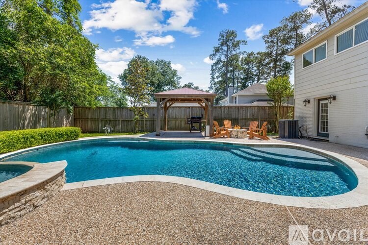 A pool with a stone border and a wooden gazebo in the background.