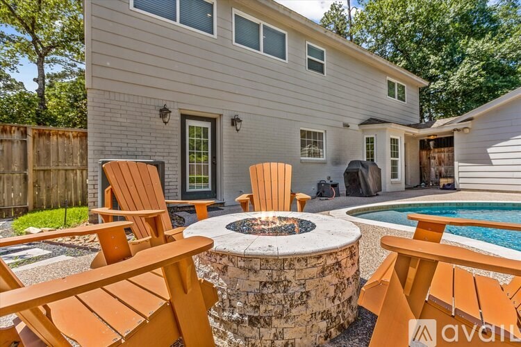 A house with a pool and a fire pit surrounded by chairs.