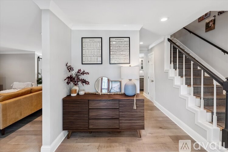 A bedroom with a bed, a dresser, and a staircase.
