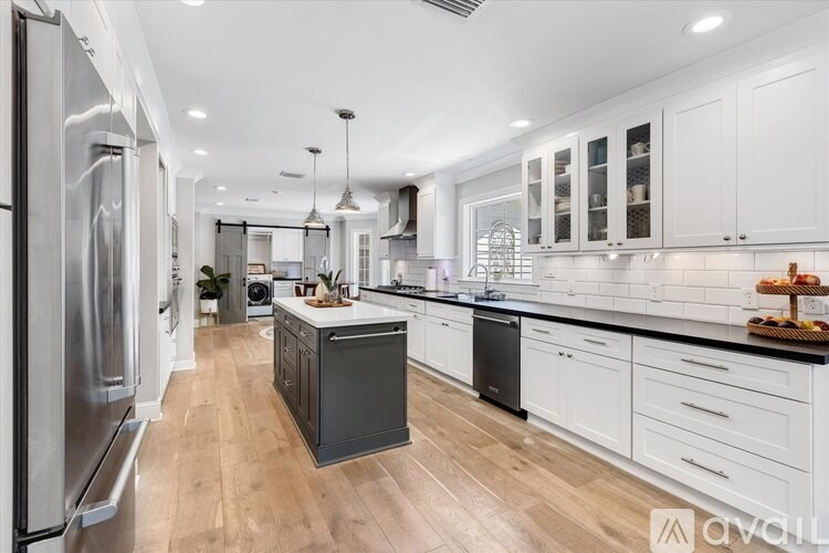 A modern kitchen with white cabinets and a wooden floor.