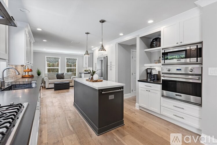 A modern kitchen with a black island and white cabinets.