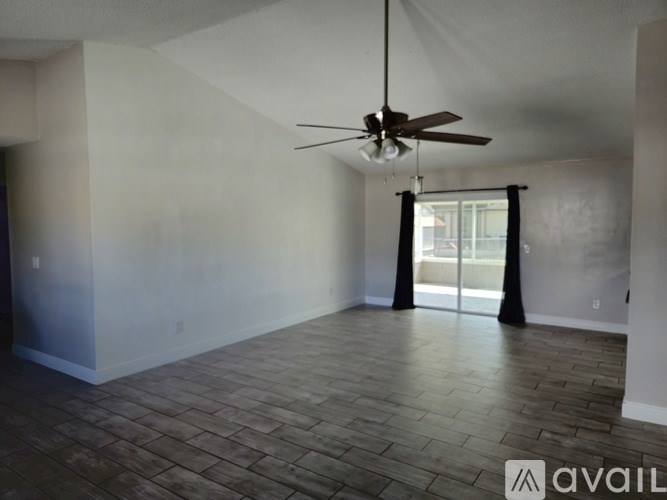 A room with a ceiling fan and sliding glass doors.
