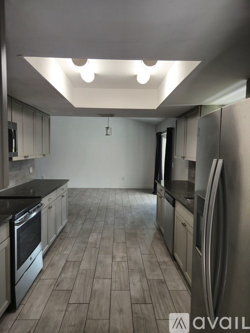 A kitchen with a black countertop and wooden flooring.