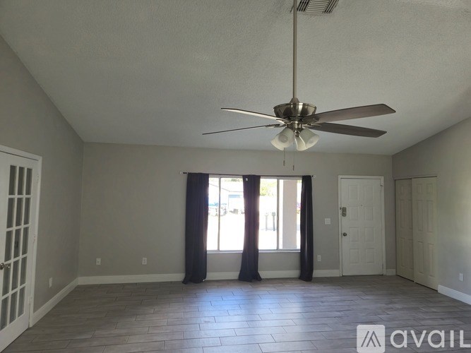 A spacious room with a ceiling fan and sliding glass doors.
