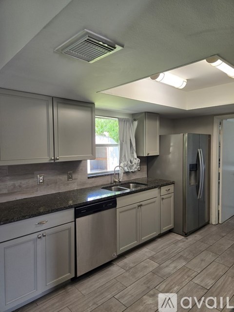A kitchen with a black dishwasher and a black fridge.