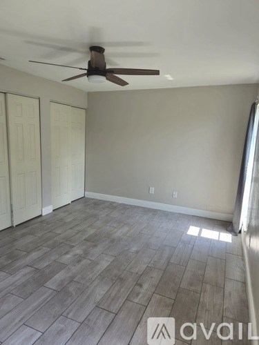 A room with a ceiling fan and wood flooring.