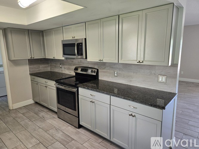 A kitchen with white cabinets and a black countertop.