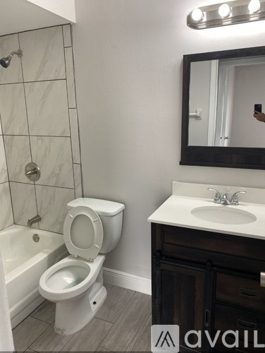 A bathroom with a toilet, sink, and mirror.