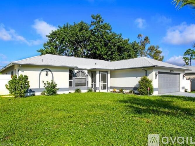 A white house with a grey roof and a green lawn in front.