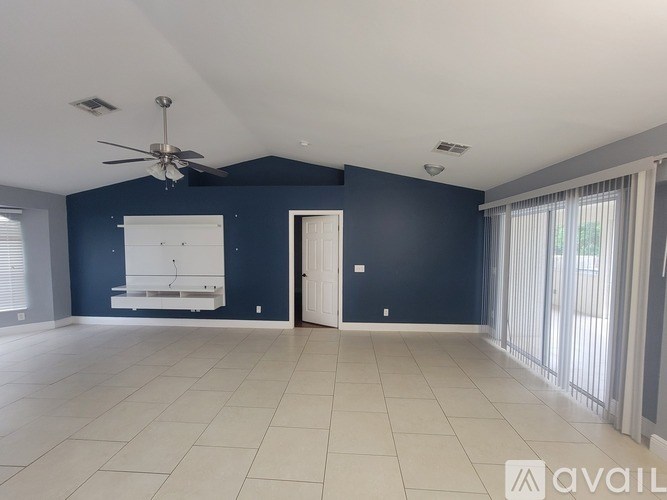 A spacious room with a ceiling fan and a white bench against a blue wall.
