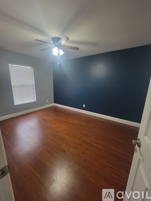 A room with a ceiling fan and wooden flooring.