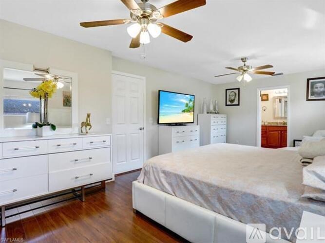 A bedroom with a large bed, a TV, and a dresser with a mirror.