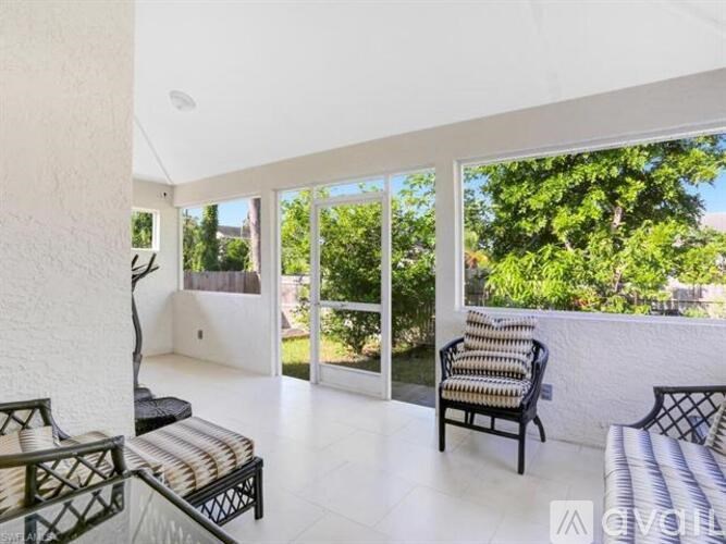 A balcony with a chair and a table overlooking a garden.