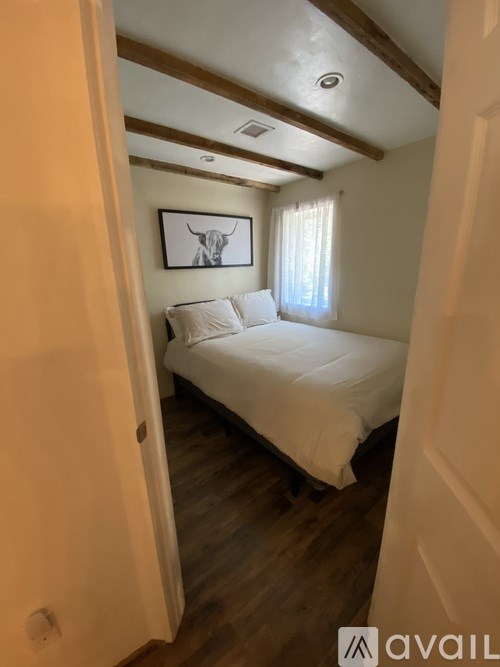 A bedroom with a bed, wooden floors, and a painting of a bull on the wall.