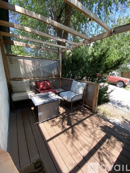 A wooden deck with a table and chairs under a pergola.
