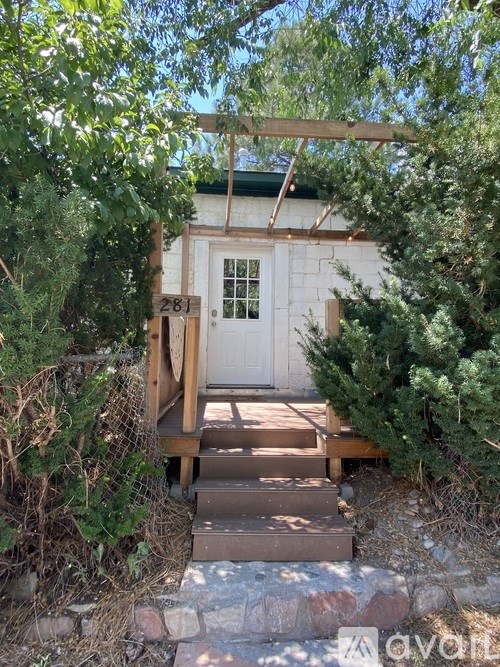 A white door with a number 281 on it is surrounded by greenery.