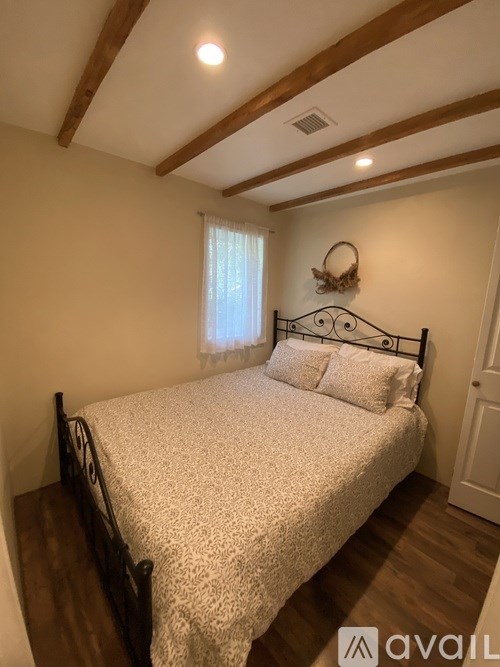 A bedroom with a bed, wooden headboard, and a window with curtains.