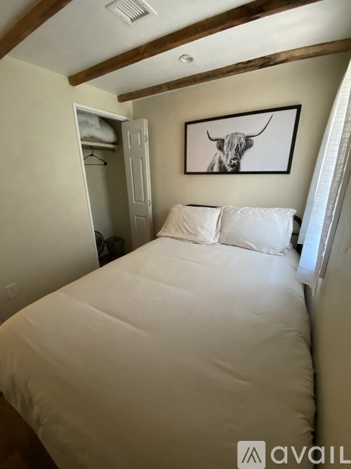 A bedroom with a white bed and a picture of a bull on the wall.
