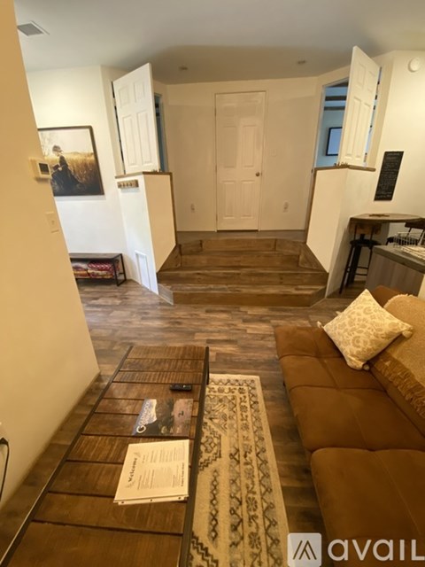 A living room with a brown couch and a rug on the floor.