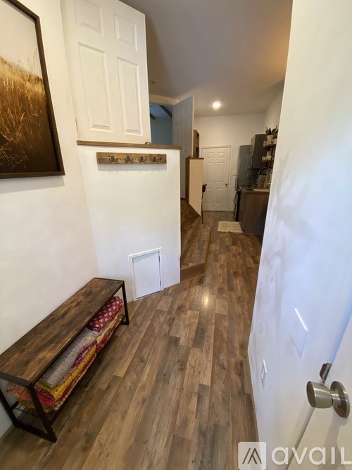 A hallway with a bench and a painting on the wall.