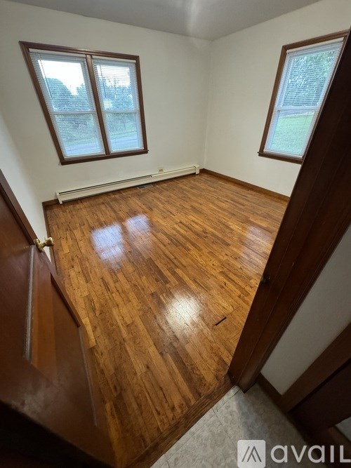 A room with wooden floors and two windows.