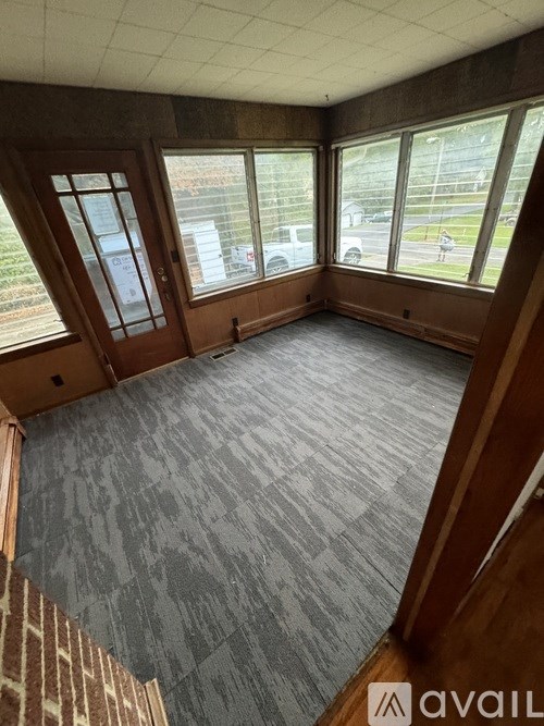 A room with a carpeted floor and a large window overlooking a parking lot.