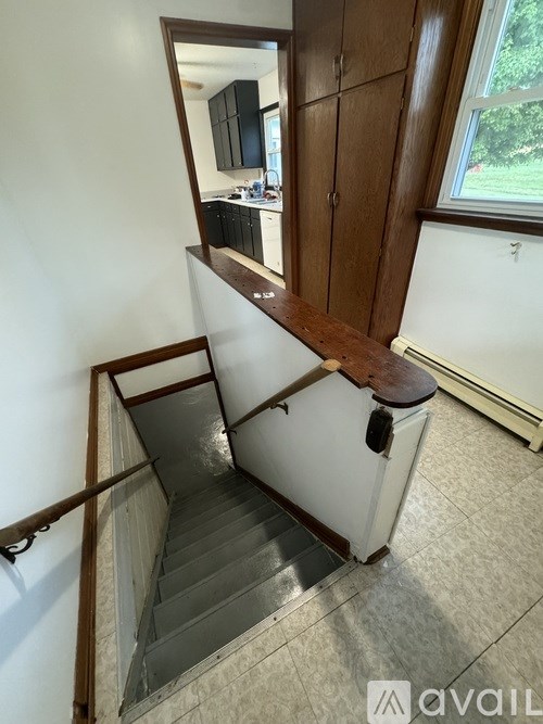 A staircase with a wooden handrail and a mirror on the wall.