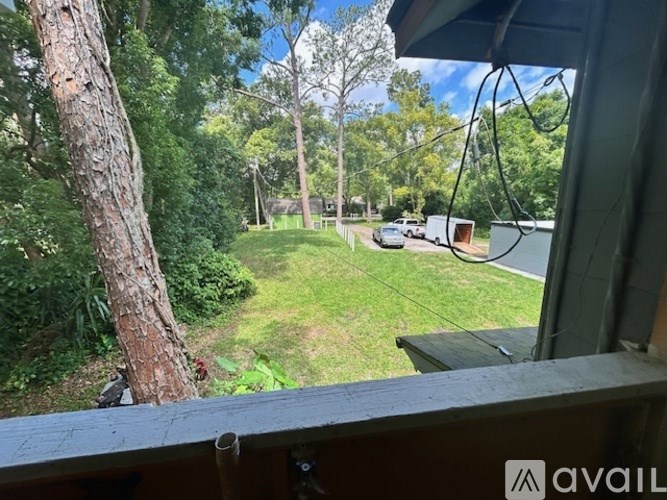 A view from a balcony looking out at a green yard and a road with vehicles.