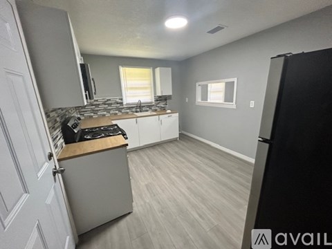 A kitchen with a black refrigerator and a countertop with a stove.