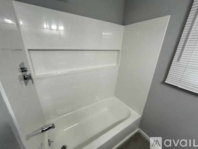 A white bathtub with a shower head and a towel bar.