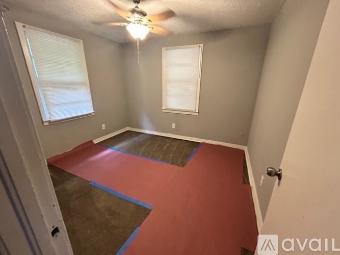 A room with a ceiling fan and two windows.