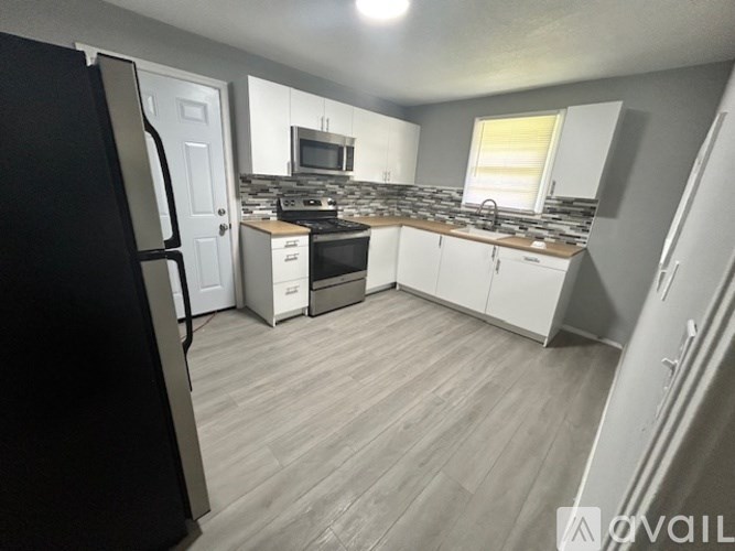 A kitchen with a refrigerator, microwave, and oven.