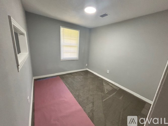 A room with a pink carpet and a window.