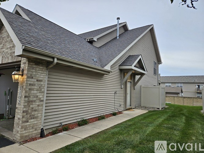 A house with a grey siding and a stone pillar.
