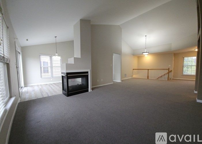 A spacious living room with a fireplace and a carpeted floor.