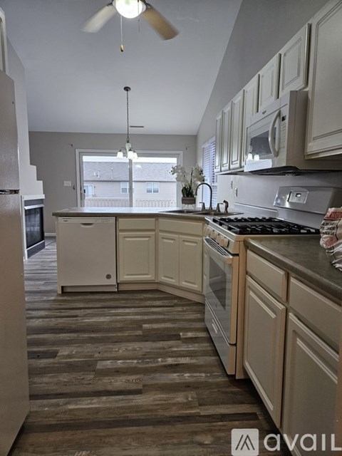 A kitchen with wooden floors and white cabinets.