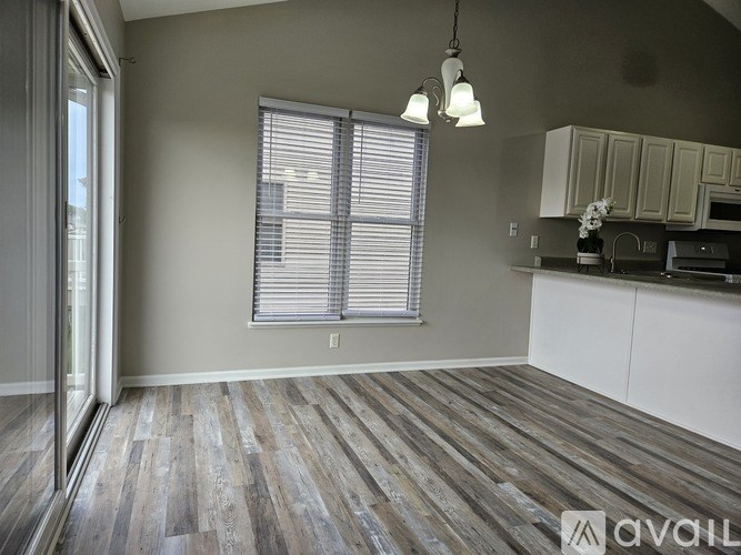 A room with wooden flooring and a window with blinds.