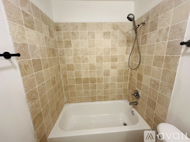 A white bathtub is in a bathroom with beige tiles.