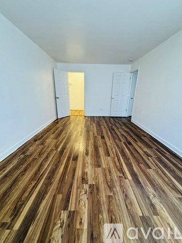 A room with wooden flooring and two doors.