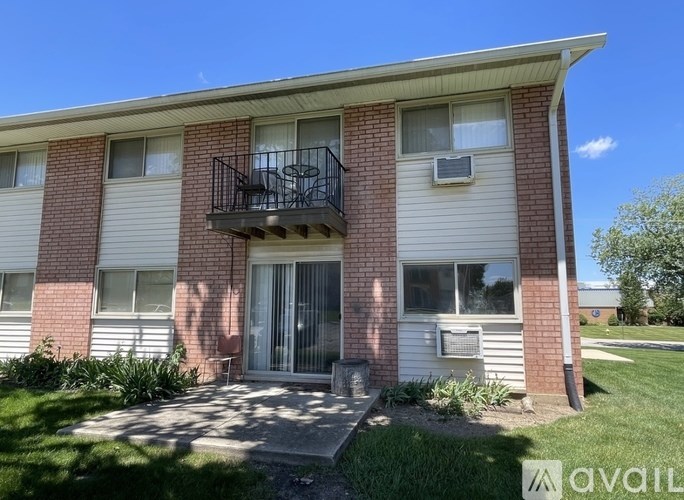 A small brick house with a balcony and a small garden in front.