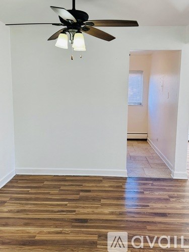 A room with a ceiling fan and wooden flooring.